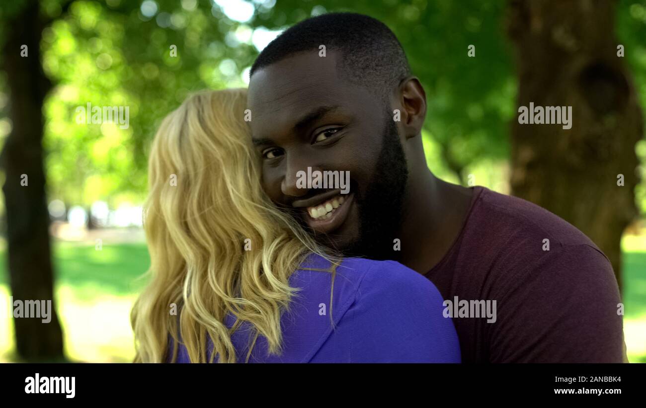 Mixed raced happy couple, black man embracing woman, interracial relationship Stock Photo