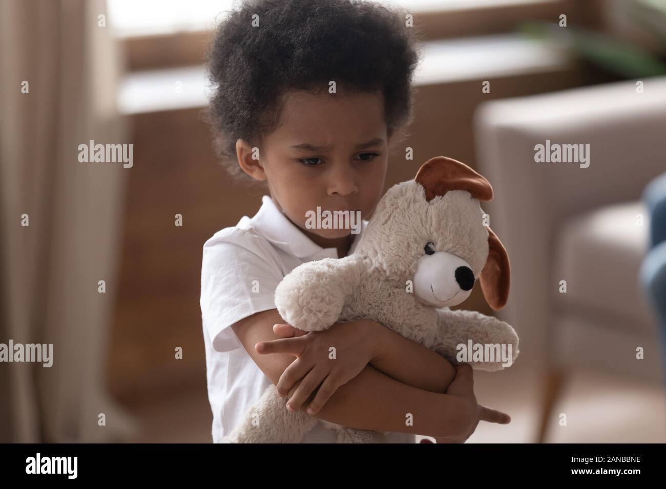 Close up cute upset lonely boy embracing favorite toy. Stock Photo