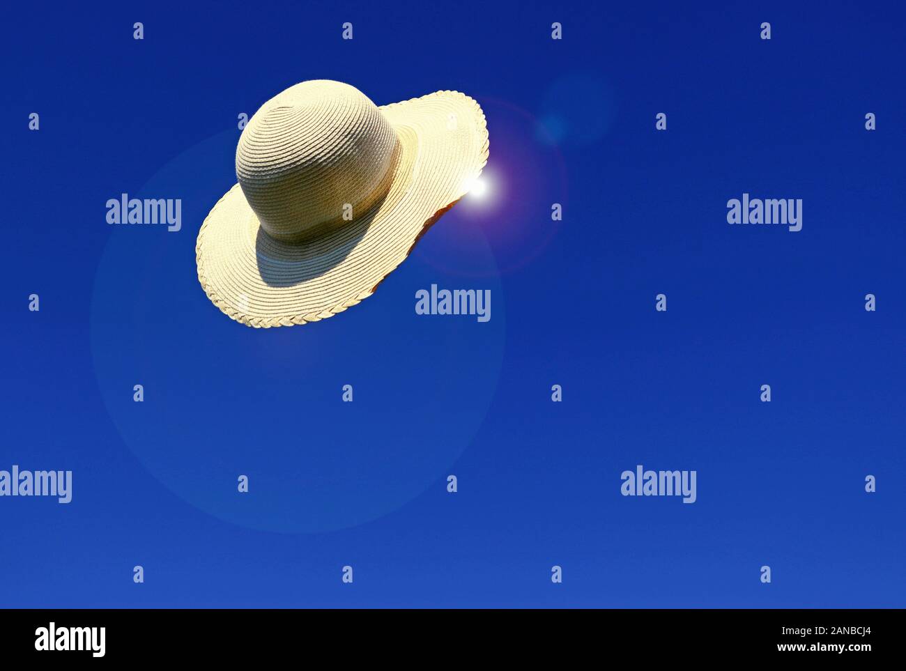 straw hat flying through the air in front of a clear blue sky, summer ...