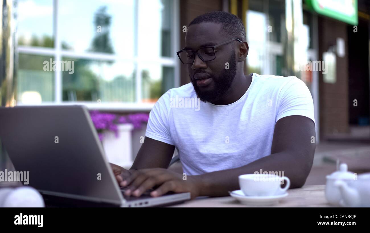 Concentrated student working on university project using laptop, sitting in cafe Stock Photo