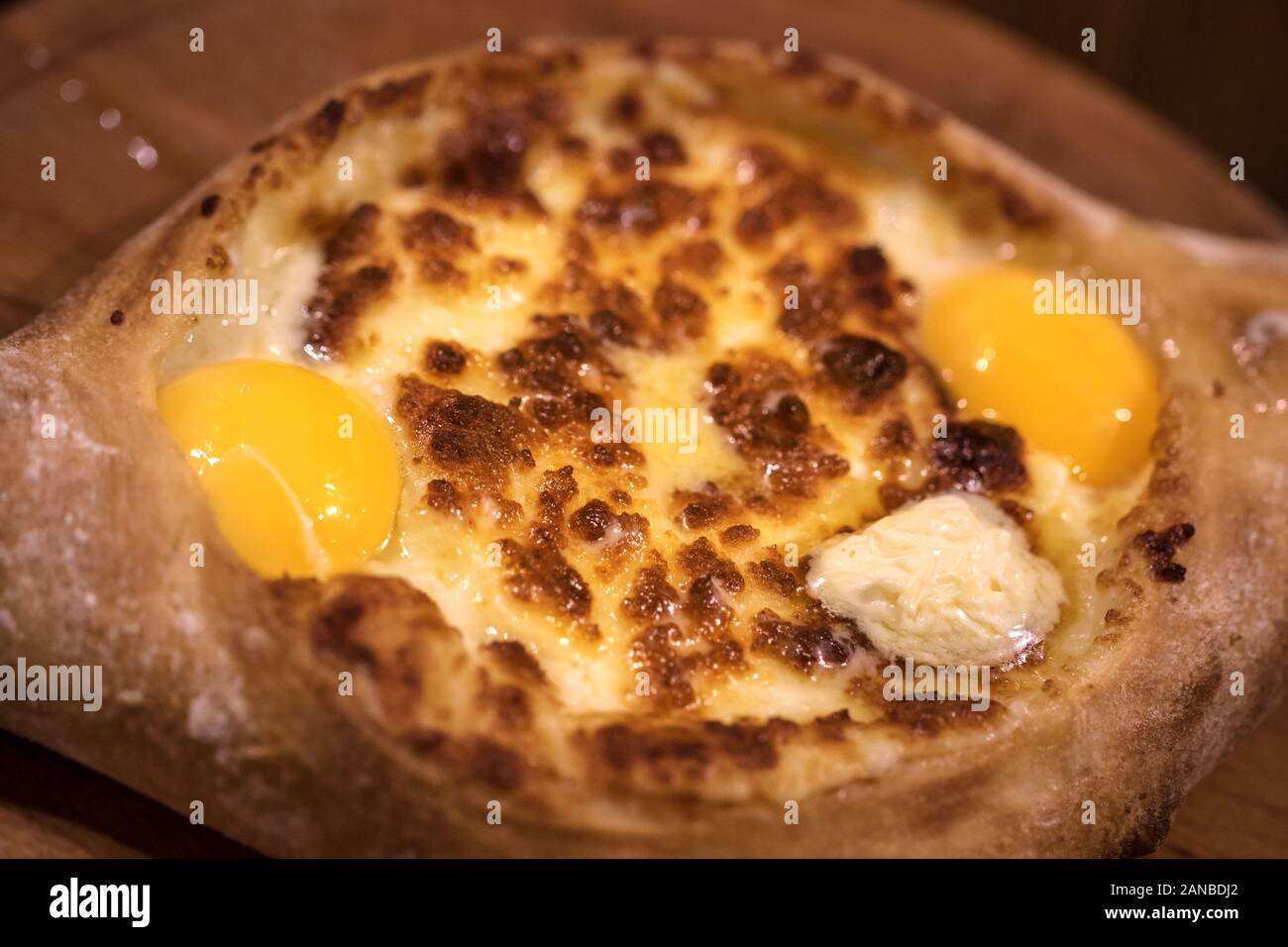 Hot Adjarian boat-shaped khachapuri, with cheese, butter, egg yolk in middle and crust at Georgian cafe.  Traditional Georgian dish of cheese-filled b Stock Photo