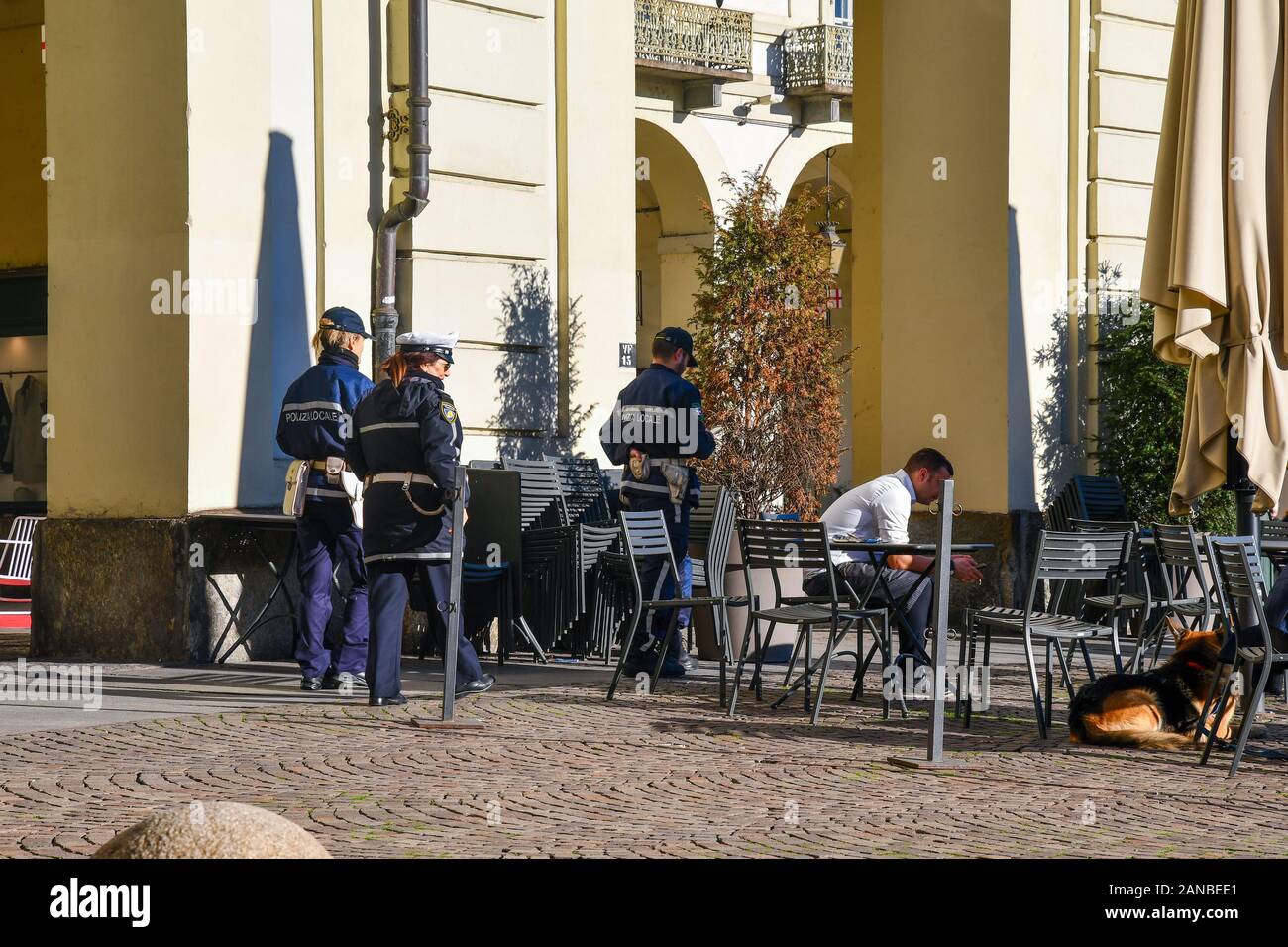 Italian police officers in Vittorio Veneto Square in the historic centre of Turin walking next to an outdoor café in a sunny day, Piedmont, Italy Stock Photo