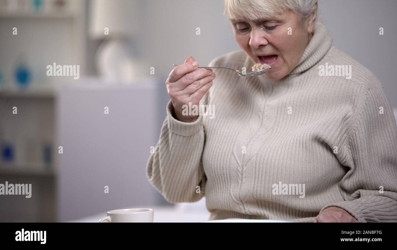 Crying elderly lady eating dinner, suffering from loneliness in old age, closeup Stock Photo
