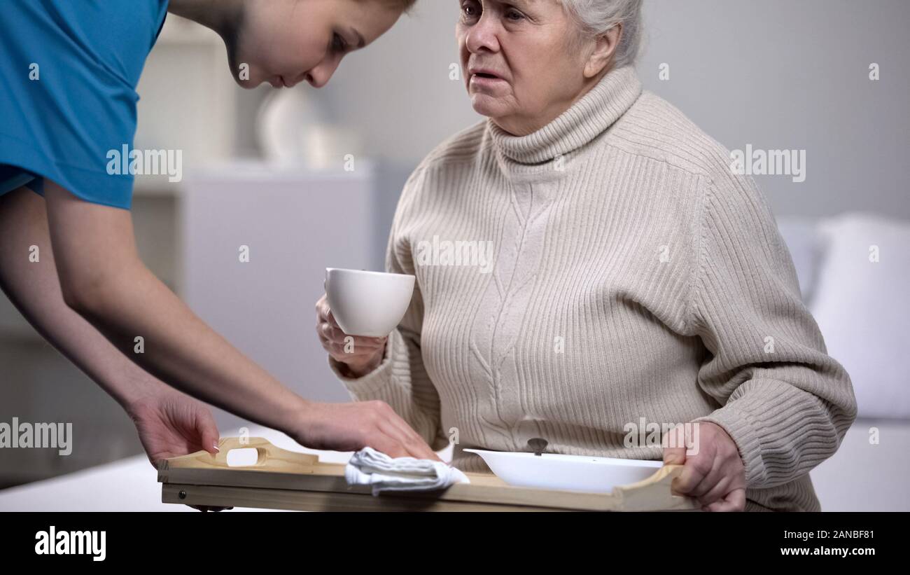 Medical worker serving dinner tray to sick elderly woman in medical center Stock Photo