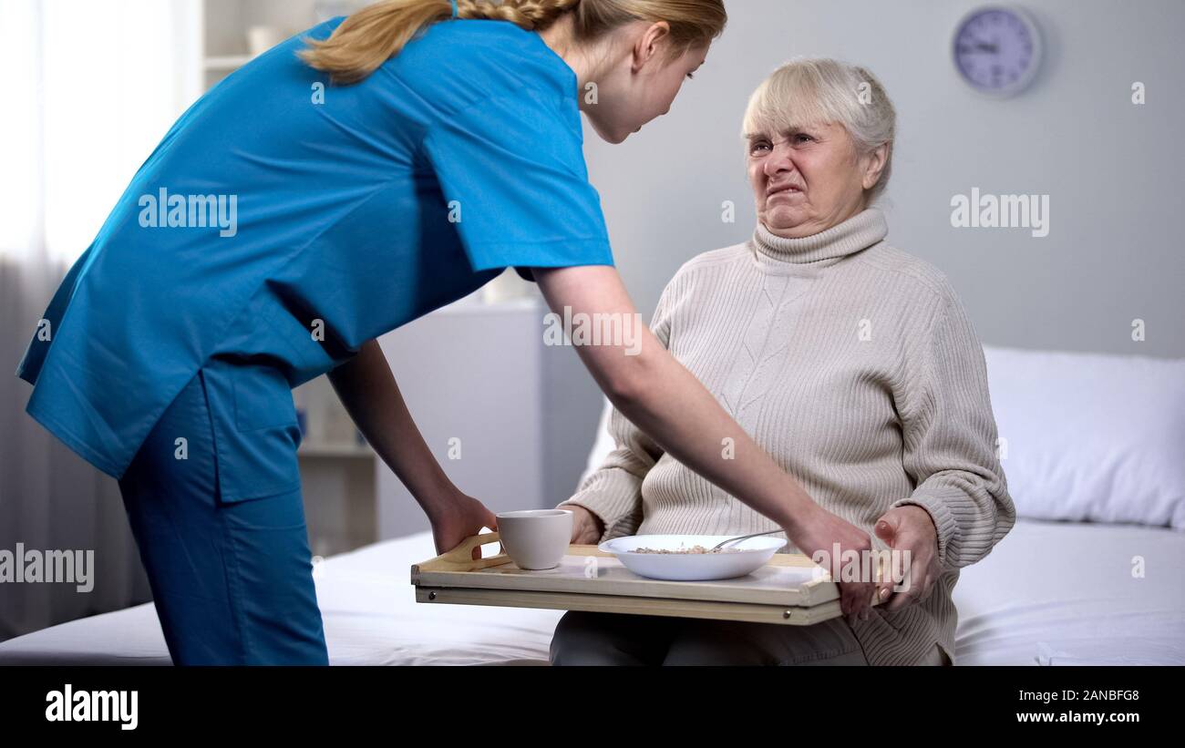 Naughty senior lady refusing disgusting diet dinner in medical center, care Stock Photo