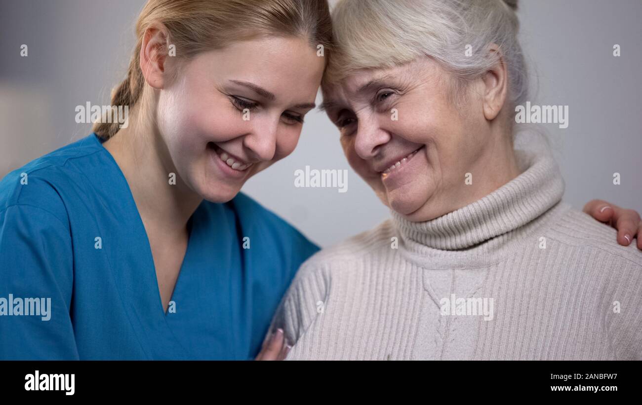 Medical worker hugging and supporting smiling elderly lady in nursing ...