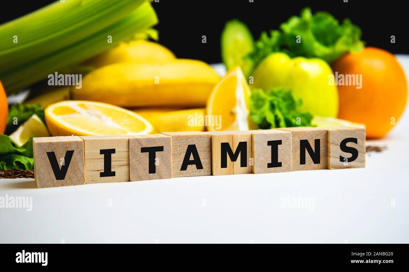 Vitamins word on wodden cubes on fruit background, diet and medical concept. Stock Photo