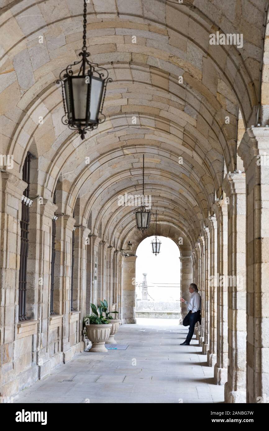 A man smokes a cigarette in the portico of city hall (ayuntamiento) in Santiago de Compostela, Spain. The city is the terminus of the Way of St. James Stock Photo