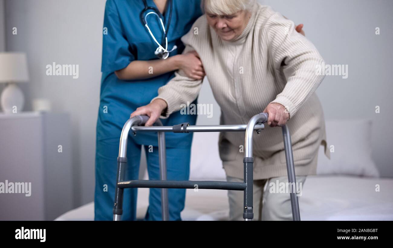 Nurse assisting patient walking frame, hip joint replacement rehabilitation Stock Photo