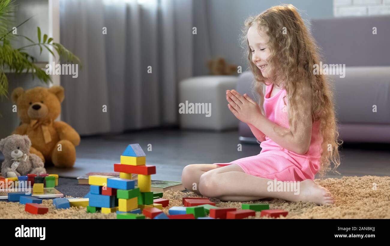 Young girl playing organic wooden blocks, kids leisure at home, education Stock Photo