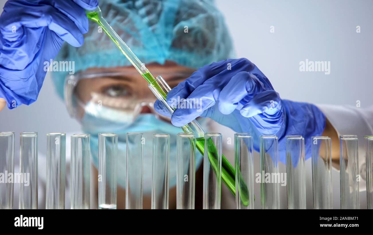 Laboratory assistant pouring green liquid into test tube, organic products Stock Photo