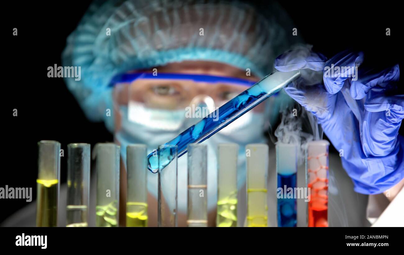Scientist holding test tube with blue liquid analyzing reaction, lab ...