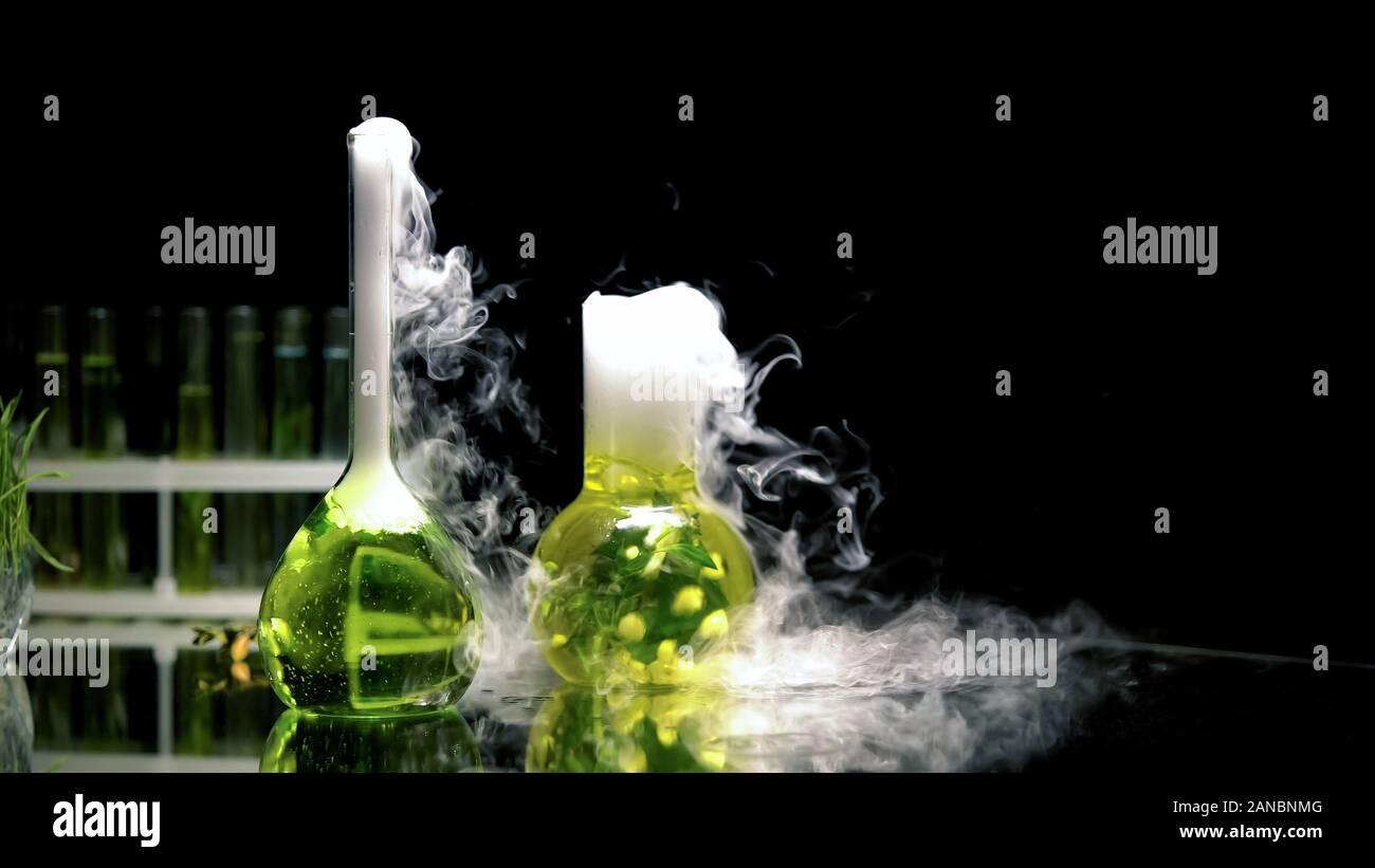 Chemical liquids in flasks bubbling and emitting smoke in darkness