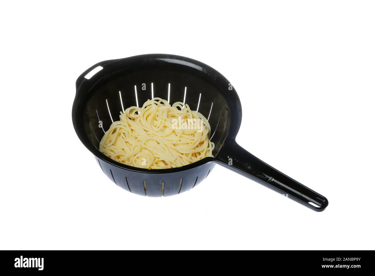 Black plastic colander filled with spaghetti isolated on white background. Stock Photo
