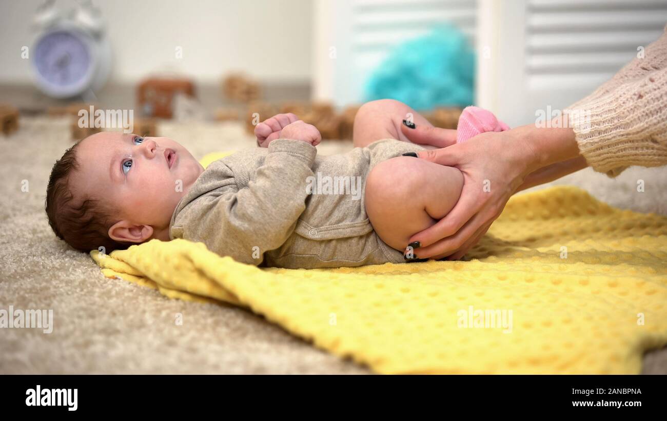 Lady massaging baby legs, thigh joints dysplasia prevention, reducing