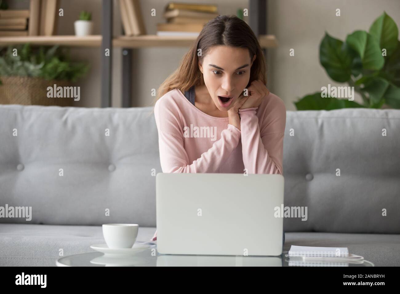 Astonished young lady stared at computer screen. Stock Photo