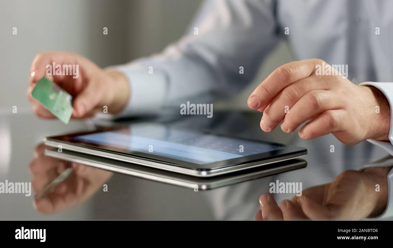Man inserting credit card number on tablet application, online banking ...