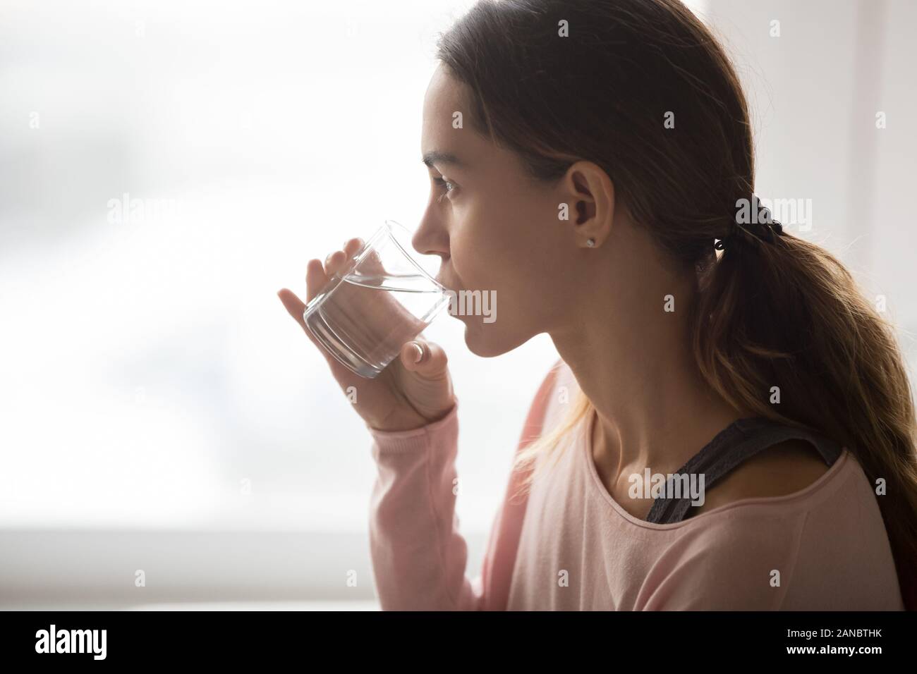 Millennial multiethnic girl drinking glass of pure water. Stock Photo