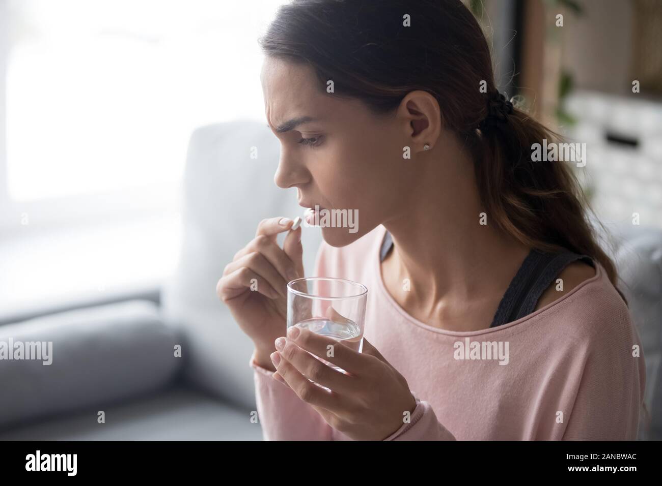 Stressed upset young girl taking medicine side view. Stock Photo