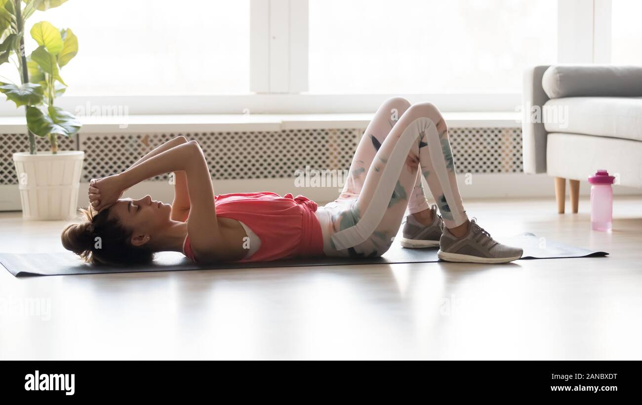 Sporty fit young woman relaxing on yoga mat at home Stock Photo - Alamy