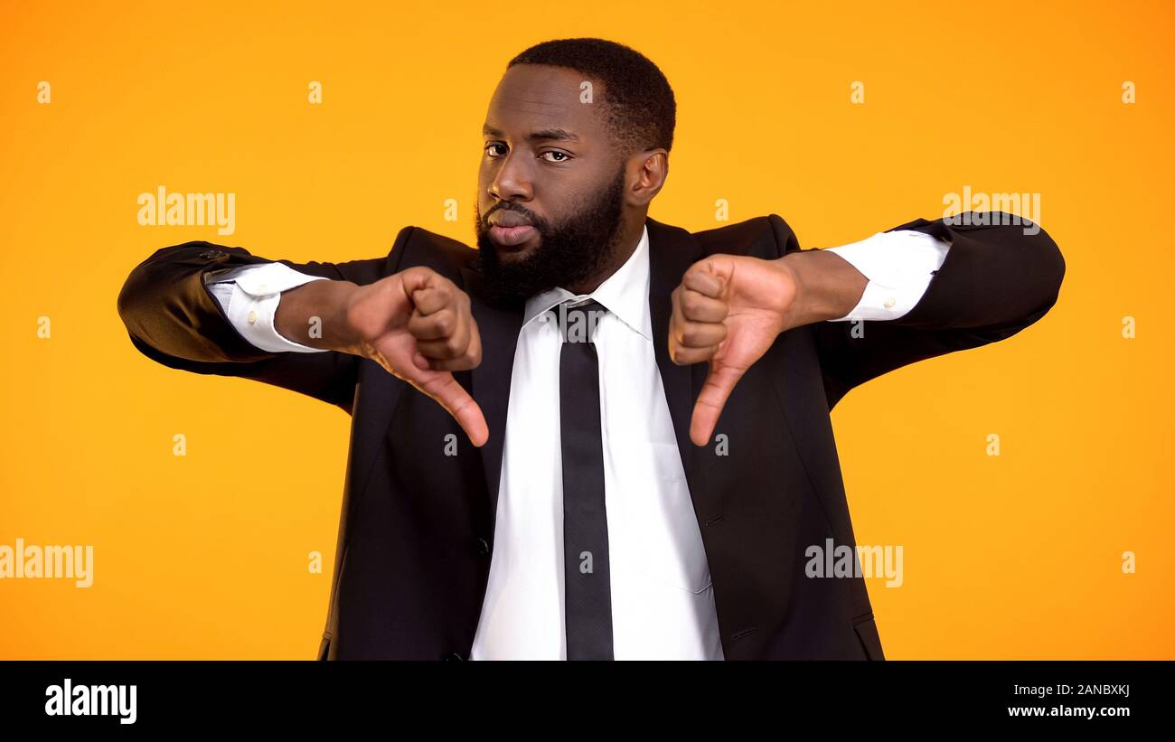 Deeply dissatisfied black man showing double thumbs-down, poor quality service Stock Photo