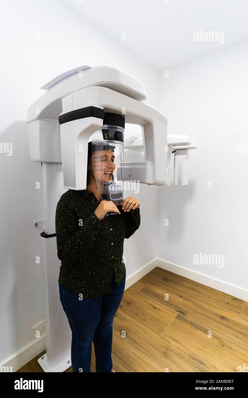 Young woman patient standing in x-ray machine. Panoramic radiography. Medical concept. Stock Photo
