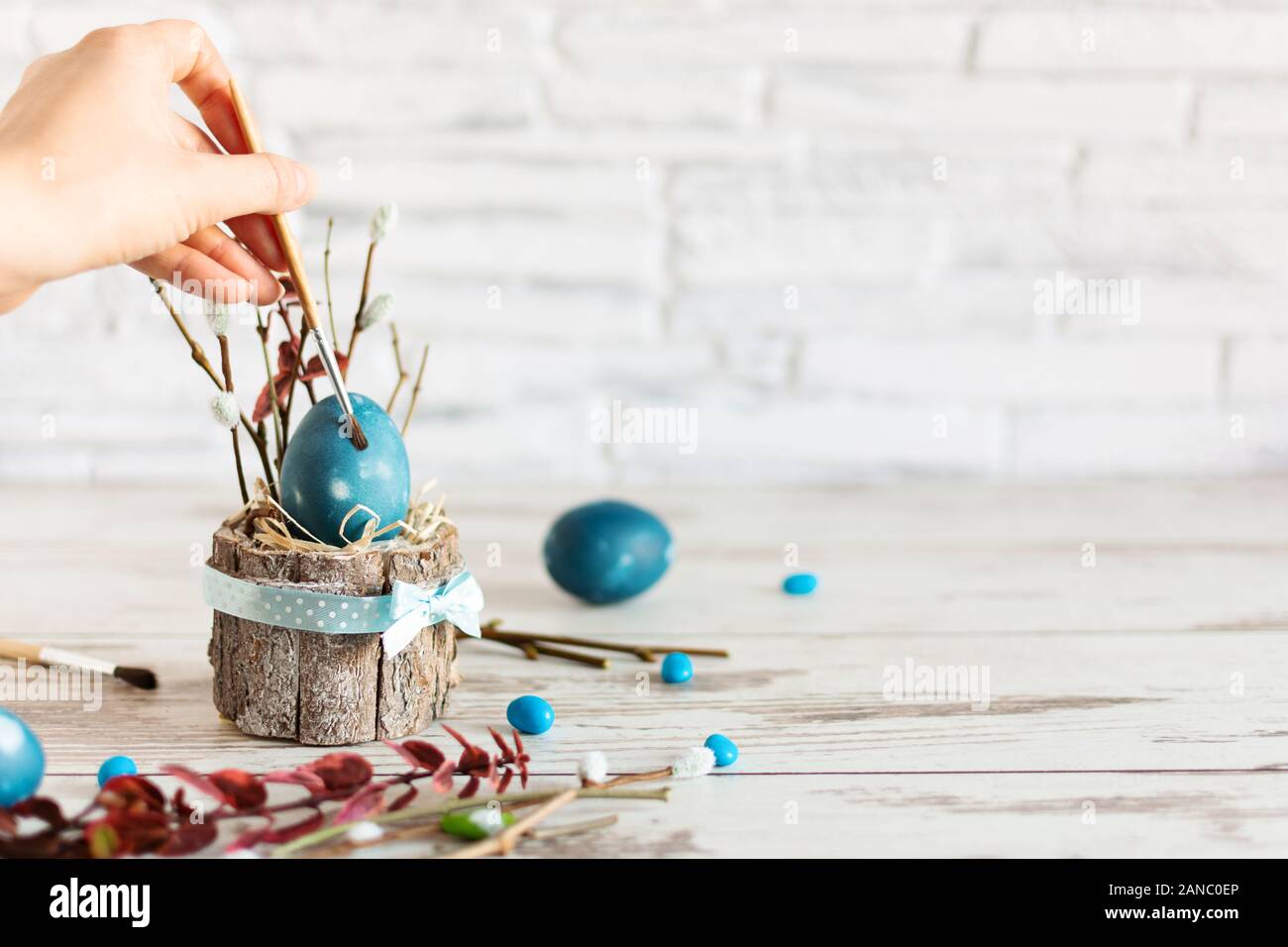 Woman hand paint Easter egg with paintbrush in modern marble classic blue color on wooden table. Happy Easter time. Creative Easter decoration. Copy s Stock Photo