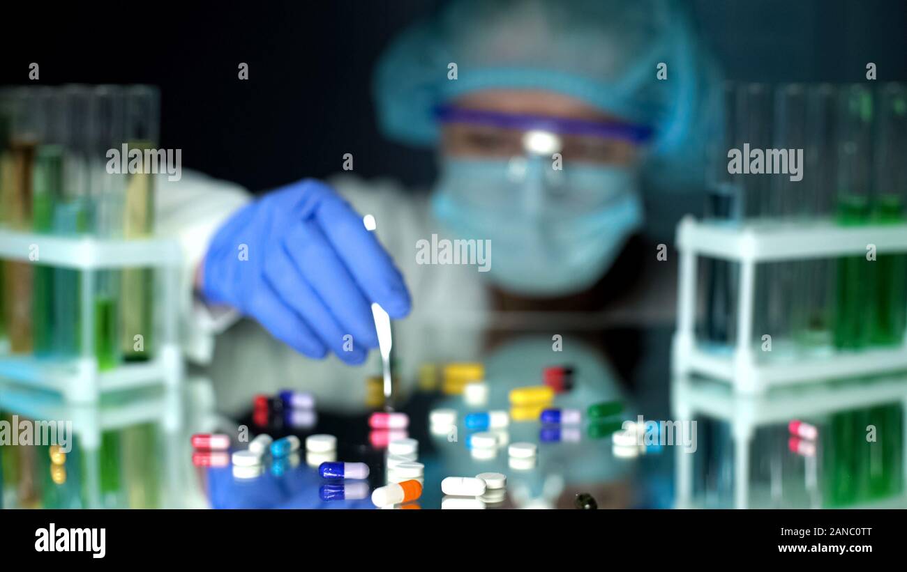 Lab assistant analyzing medication capsules, counterfeit ...