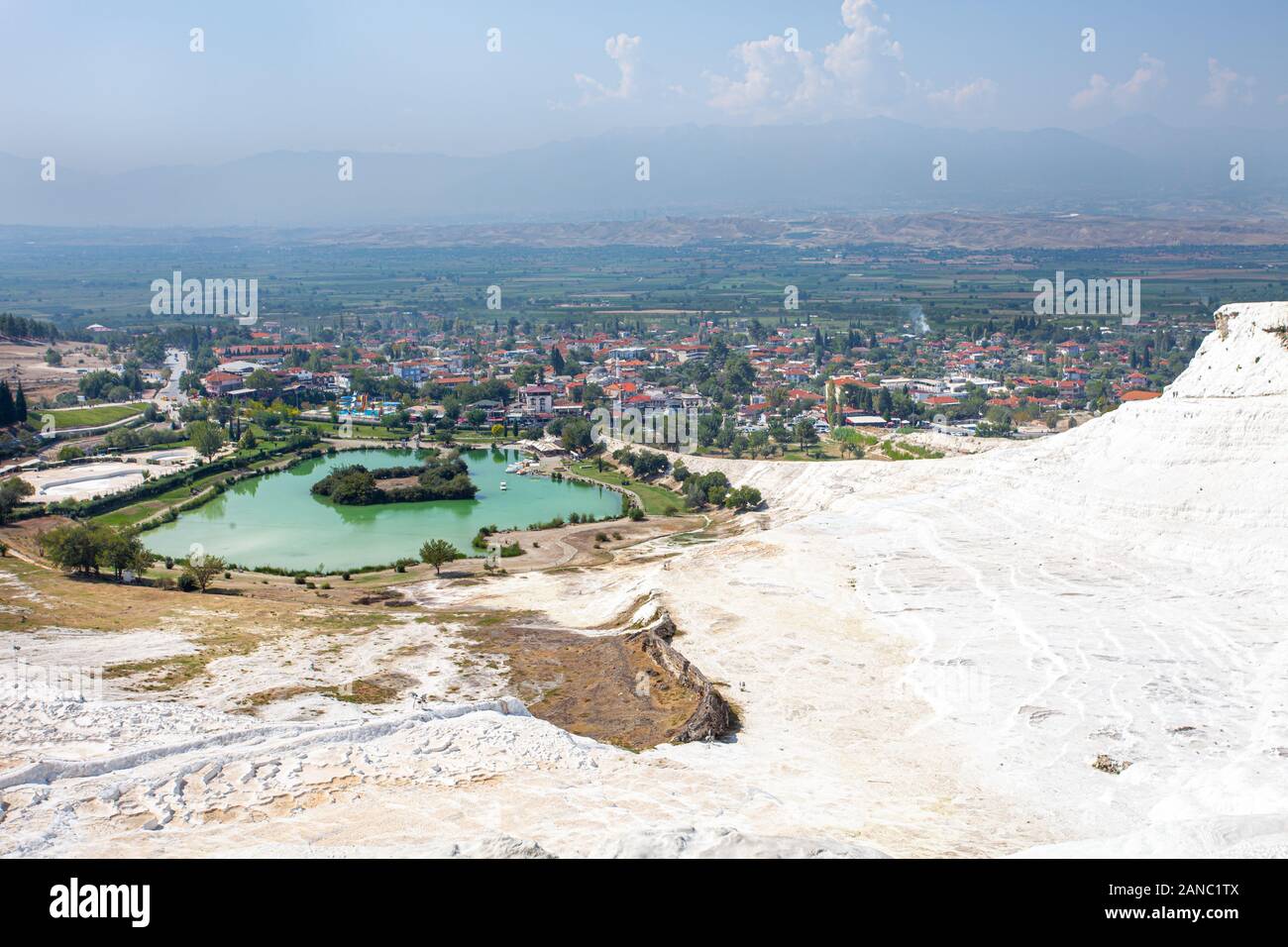 View of the unique Pamukkale natural complex with white cliffs, an emerald lake, a picturesque village and a beautiful valley. Stock Photo