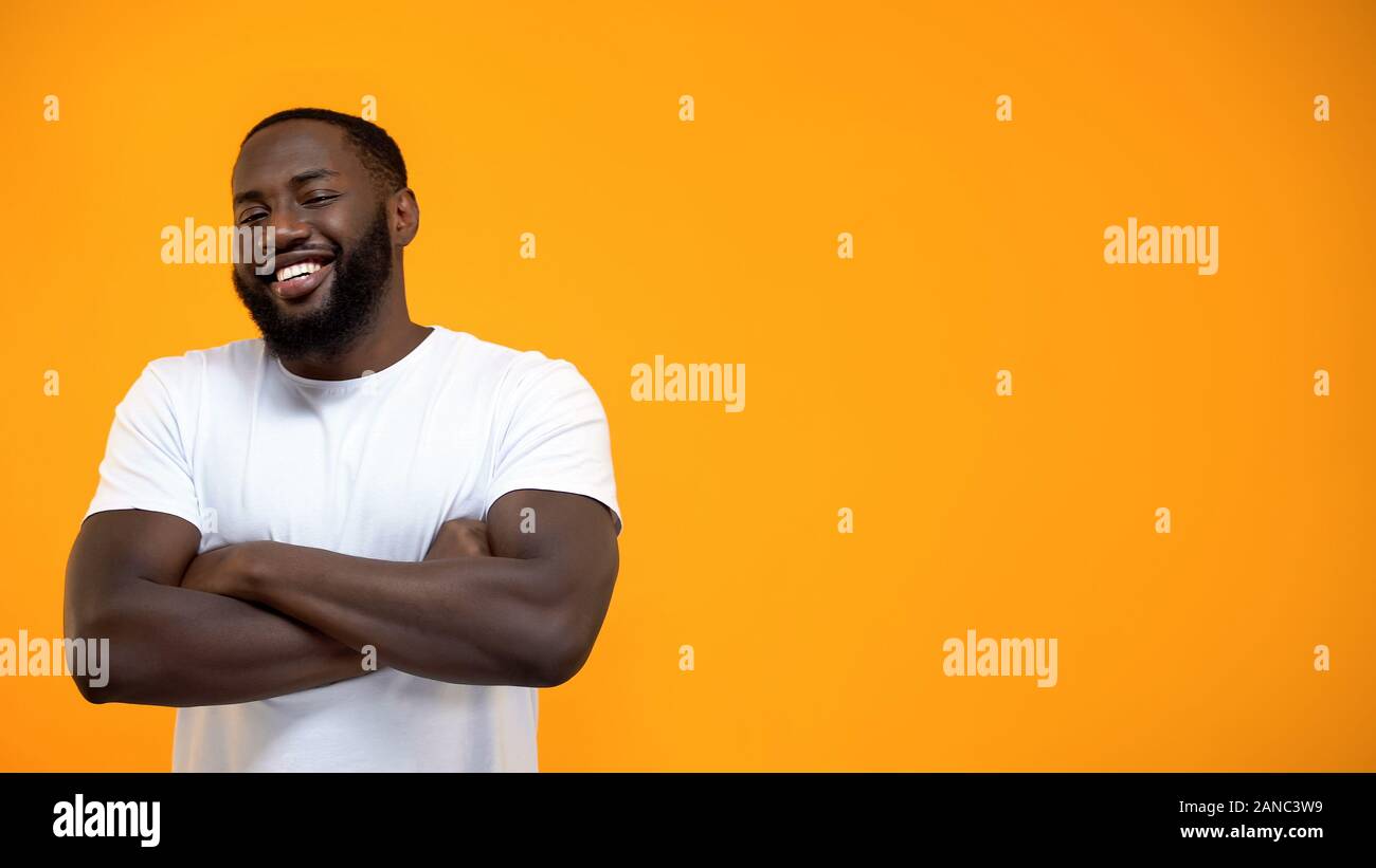 Handsome Afro-American man standing with hands crossed, looking at camera Stock Photo