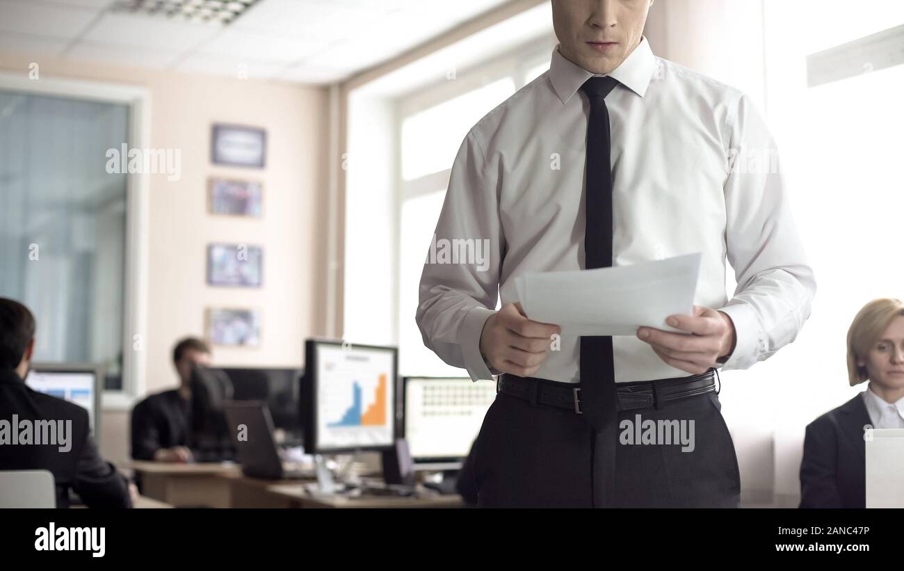 Serious businessman reading contract, office employees working on background Stock Photo
