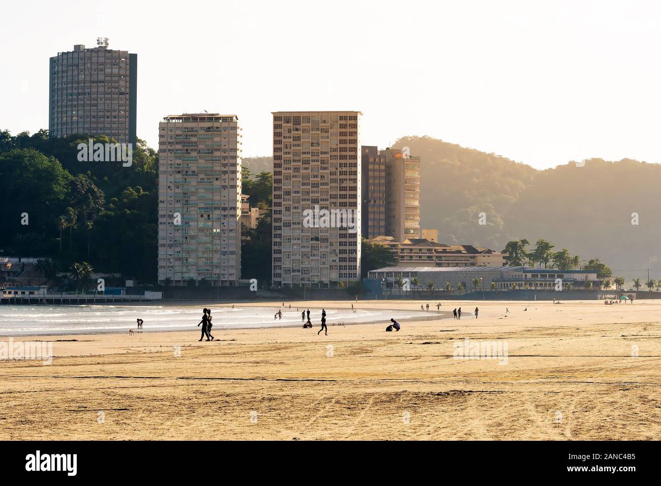 View of Praia do Itarare beach and the Ilha Porchat island on the background. People on a brazilian beach on a sunny day. Photo taken at Sao Vicente S Stock Photo