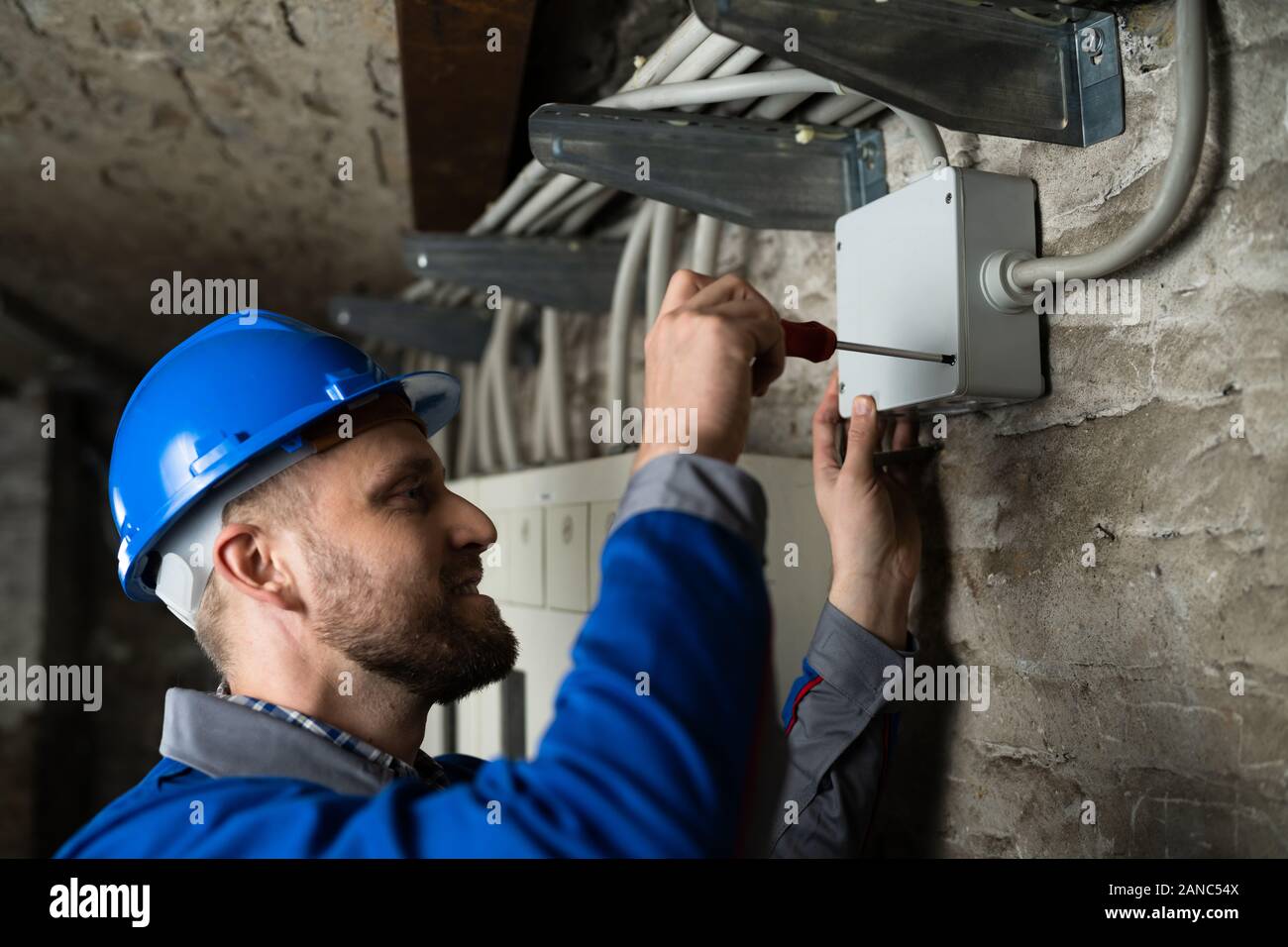 Close-up Of Young Male Technician Opening Cable Box With Screwdriver Stock Photo