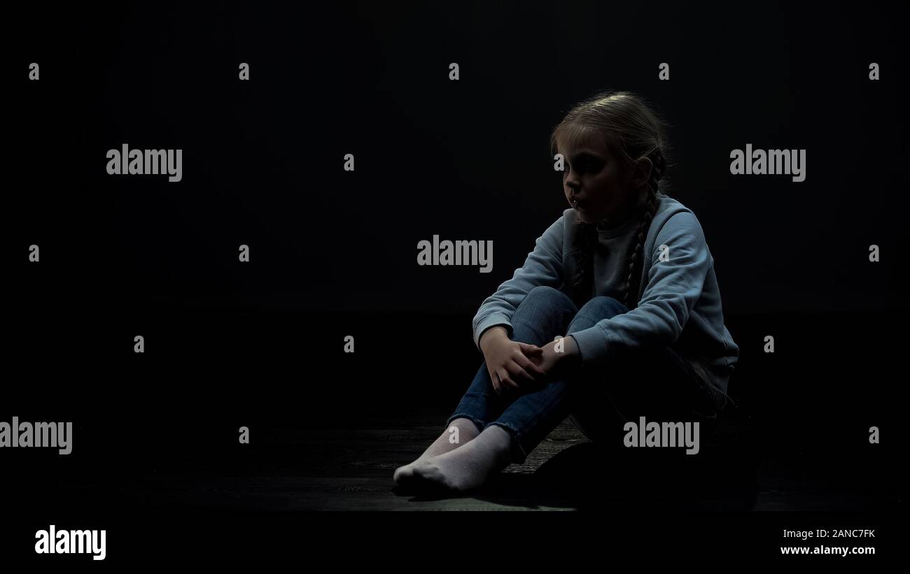 Upset little girl sitting in dark room alone, fear and problems, orphan kid Stock Photo Alamy