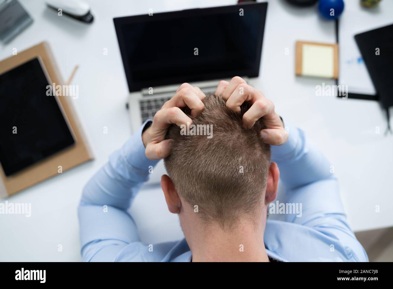 High Angle View Of Young Stressed Businessman In Front Of Laptop At Desk Stock Photo