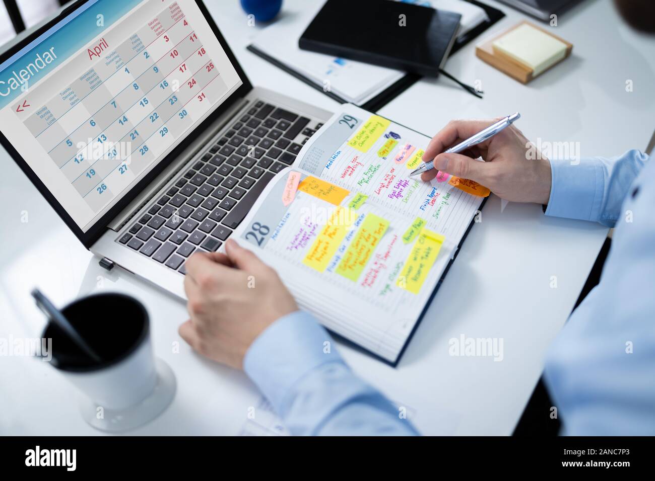 Close-up Of Businessman Writing Schedule In Calendar Diary On Desk Stock Photo