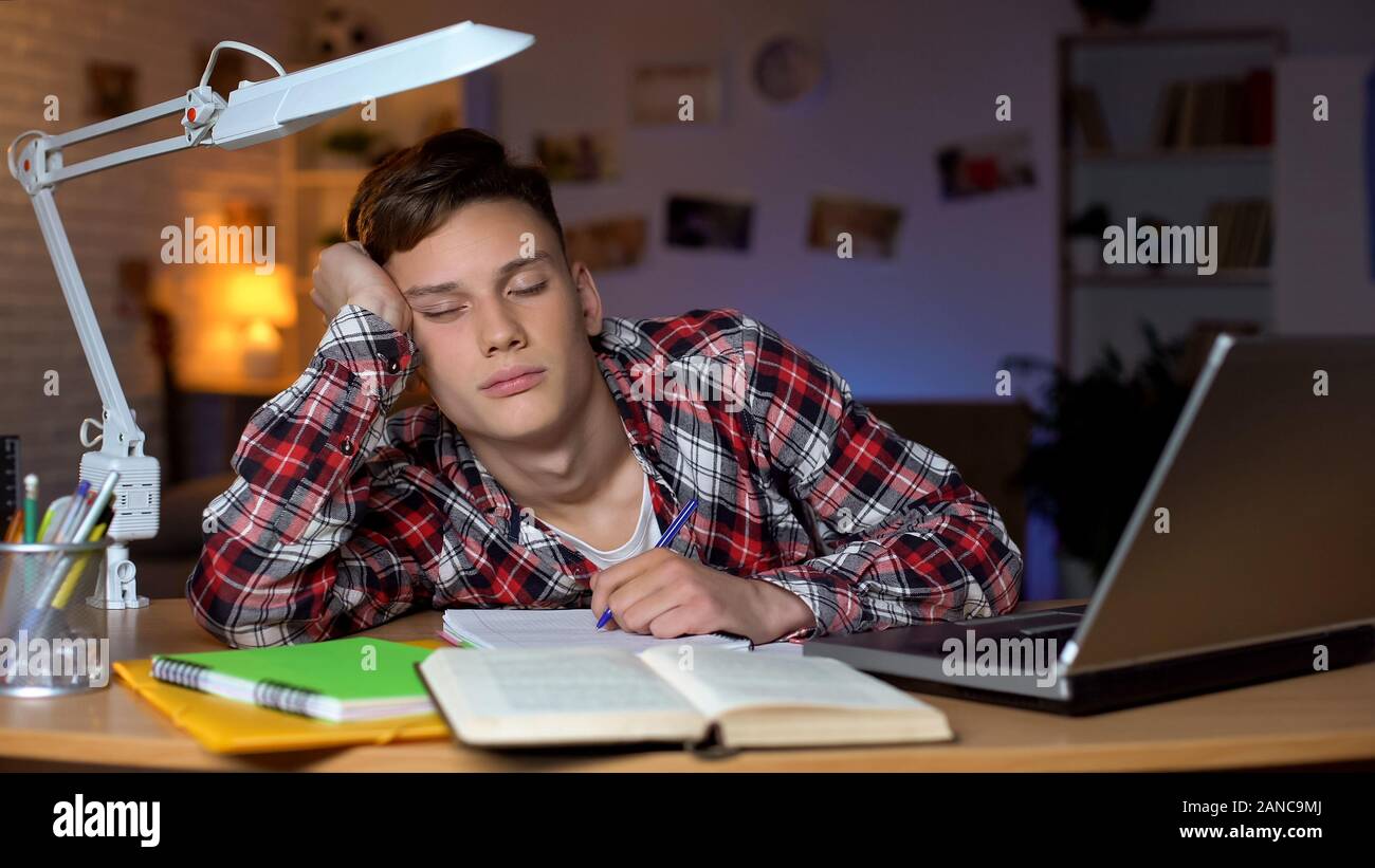 Left-handed overloaded teenage student preparing for examination, feeling sleepy Stock Photo