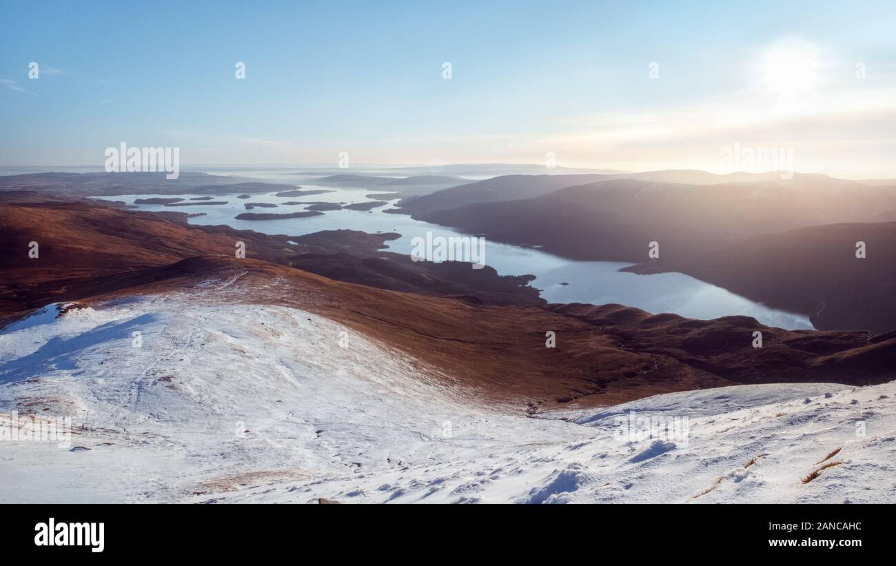 Top view of a lake and mountains partially covered with snow, lit by the sun. Loch Lomond and The Trossachs National Park. Scotland Stock Photo