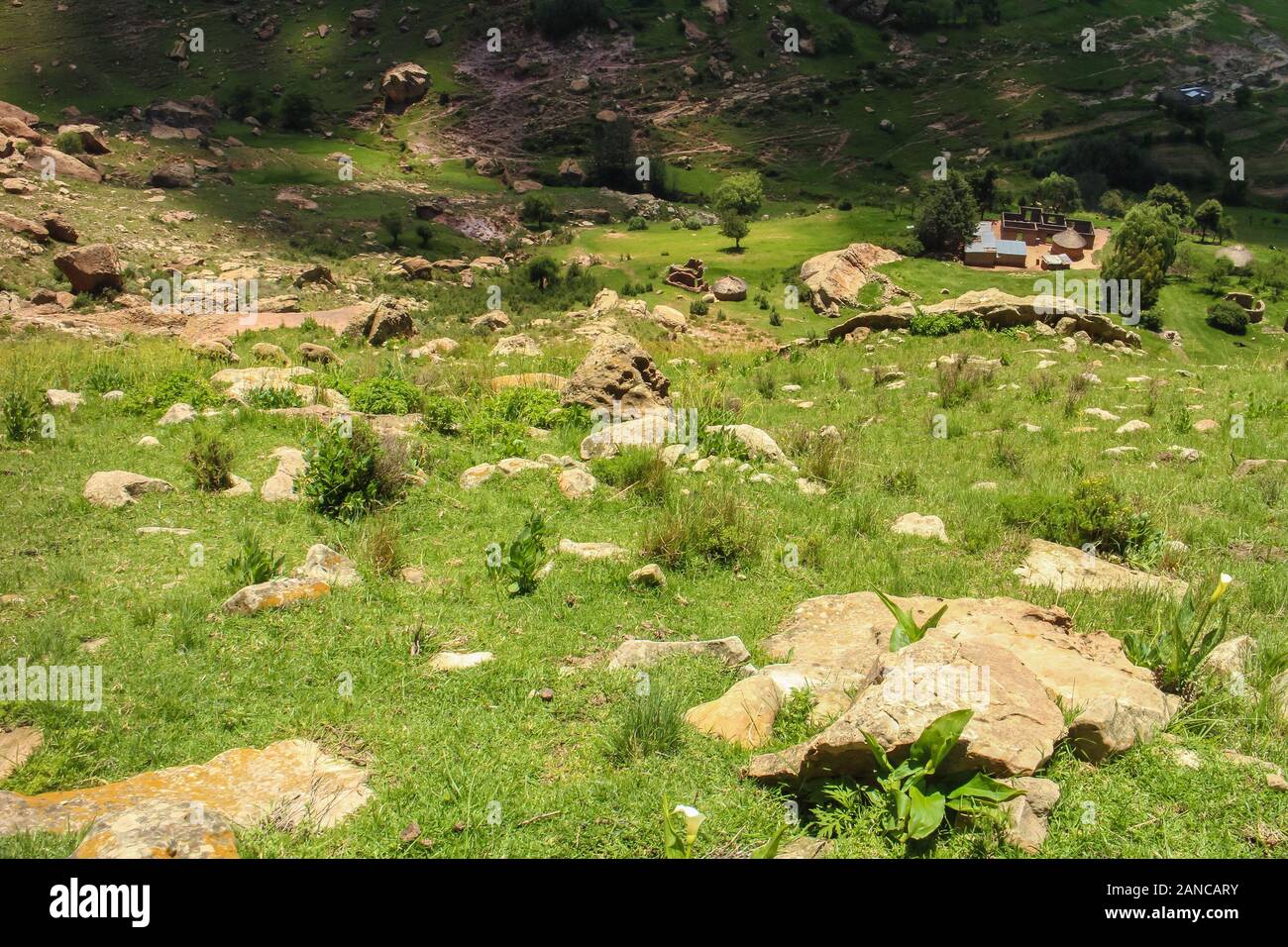 Hiking in the Drakensberg mountains of Lesotho with a small traditional village in the valley. Stock Photo