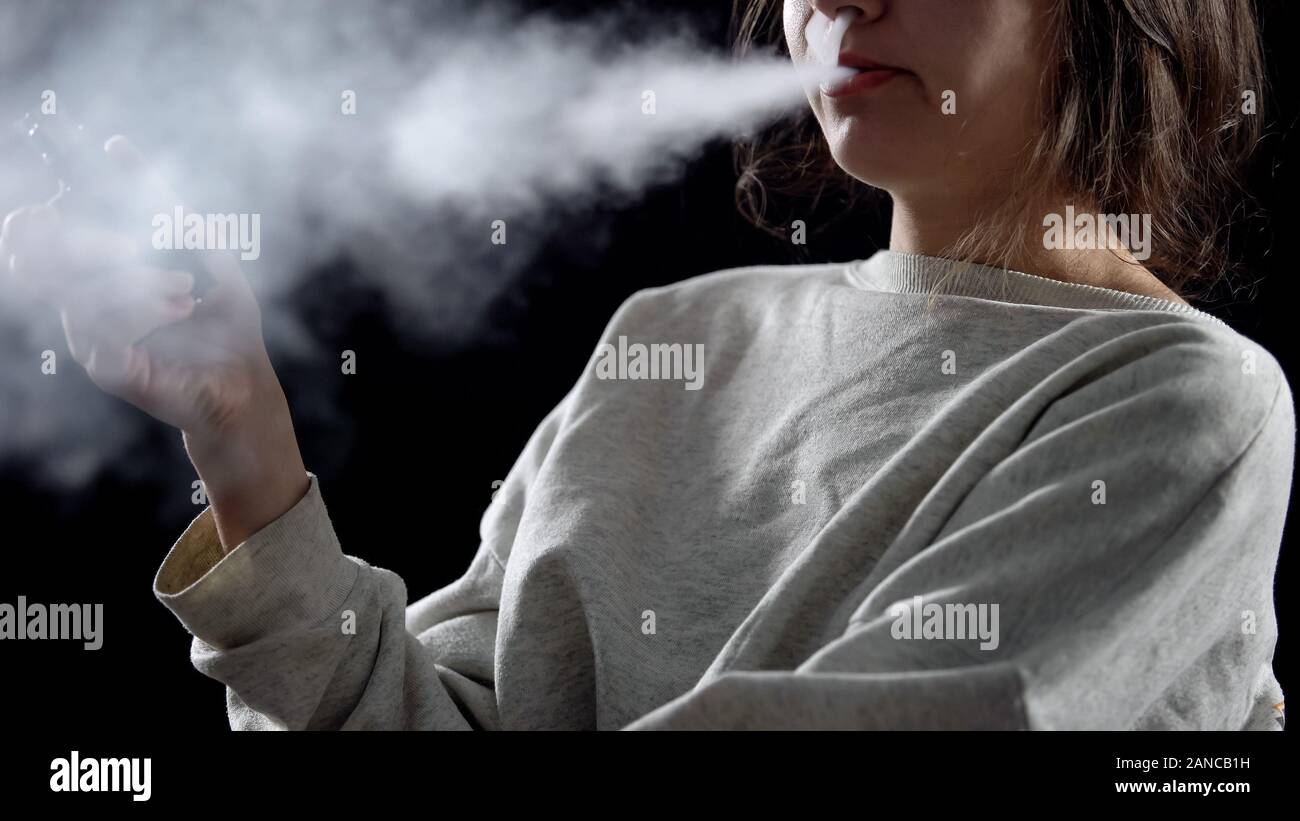 Woman exhaling vapor with electronic cigarette, device for smoking simulation Stock Photo