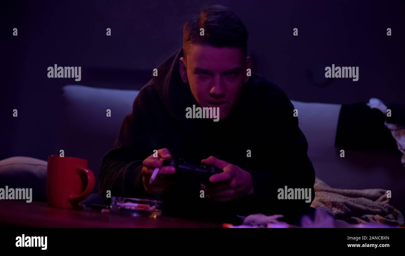 Aggressive teenage boy smoking and playing video game, nicotine