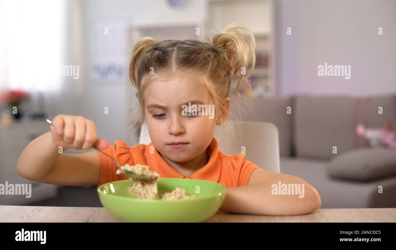 Unhappy girl looking at oatmeal, healthy but tasteless nutrition, dieting Stock Photo
