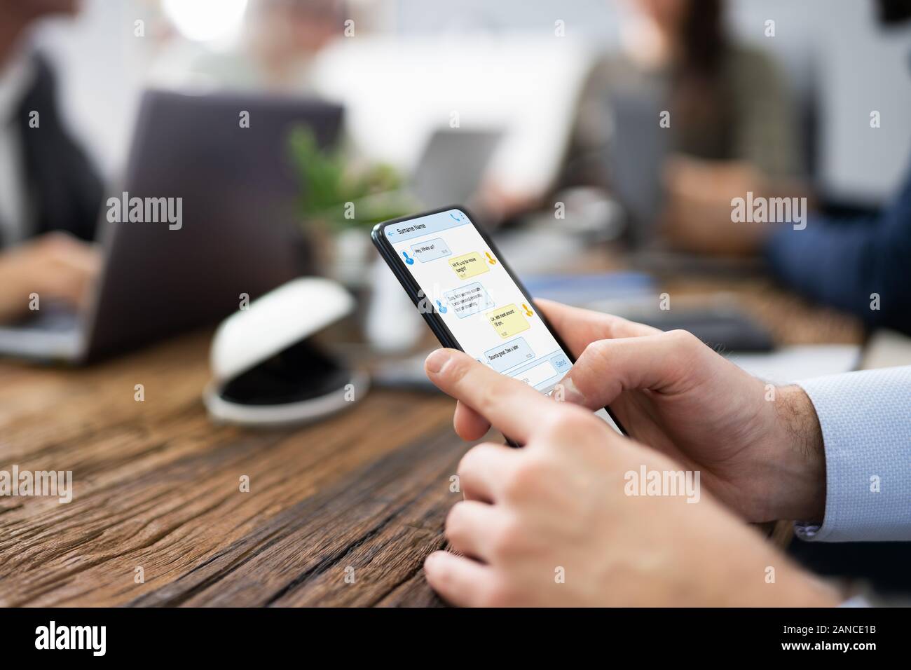 Distracted Businessman Using Mobile Phone In Meeting Stock Photo