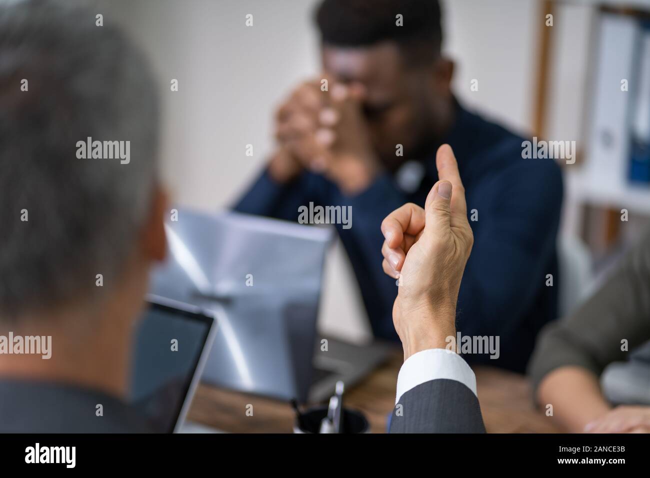 Close-up Of Businessperson Quarreling To Young Colleague At Desk Stock Photo