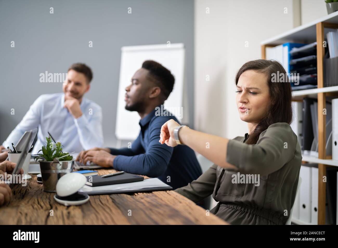 Woman Checking Time While Sitting In A Boring Long Meeting Stock Photo