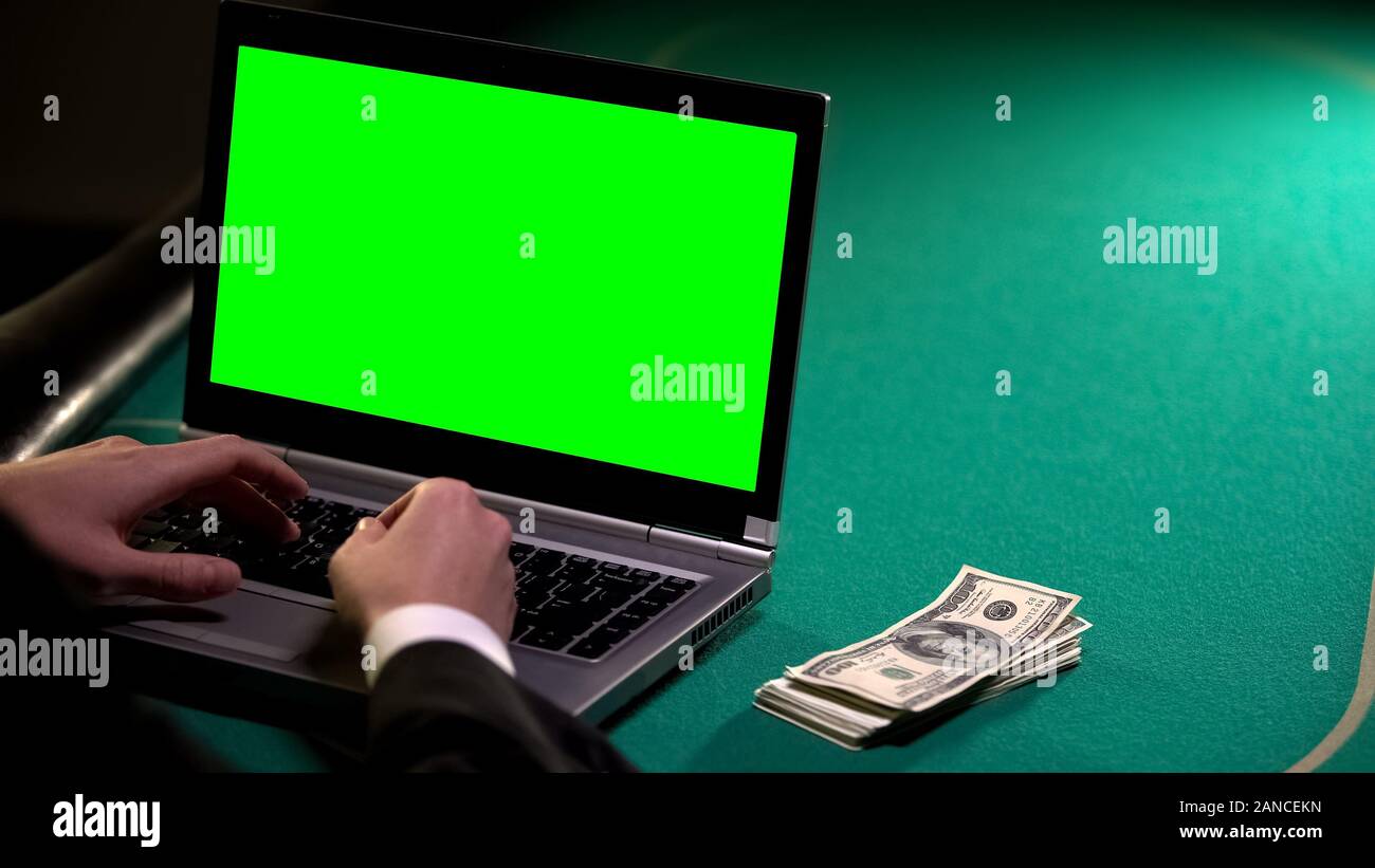 Man using laptop on poker table, earning money in online betting, gambling Stock Photo