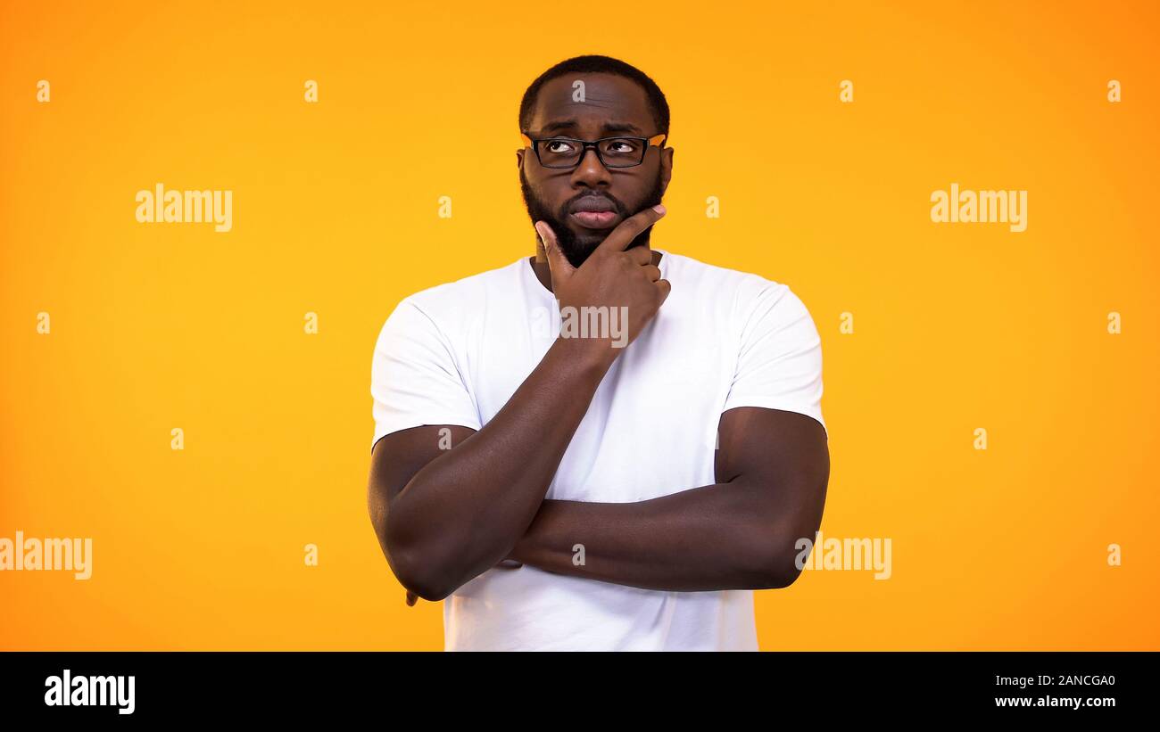 Smart young black student in glasses thinking about answer, yellow  background Stock Photo - Alamy