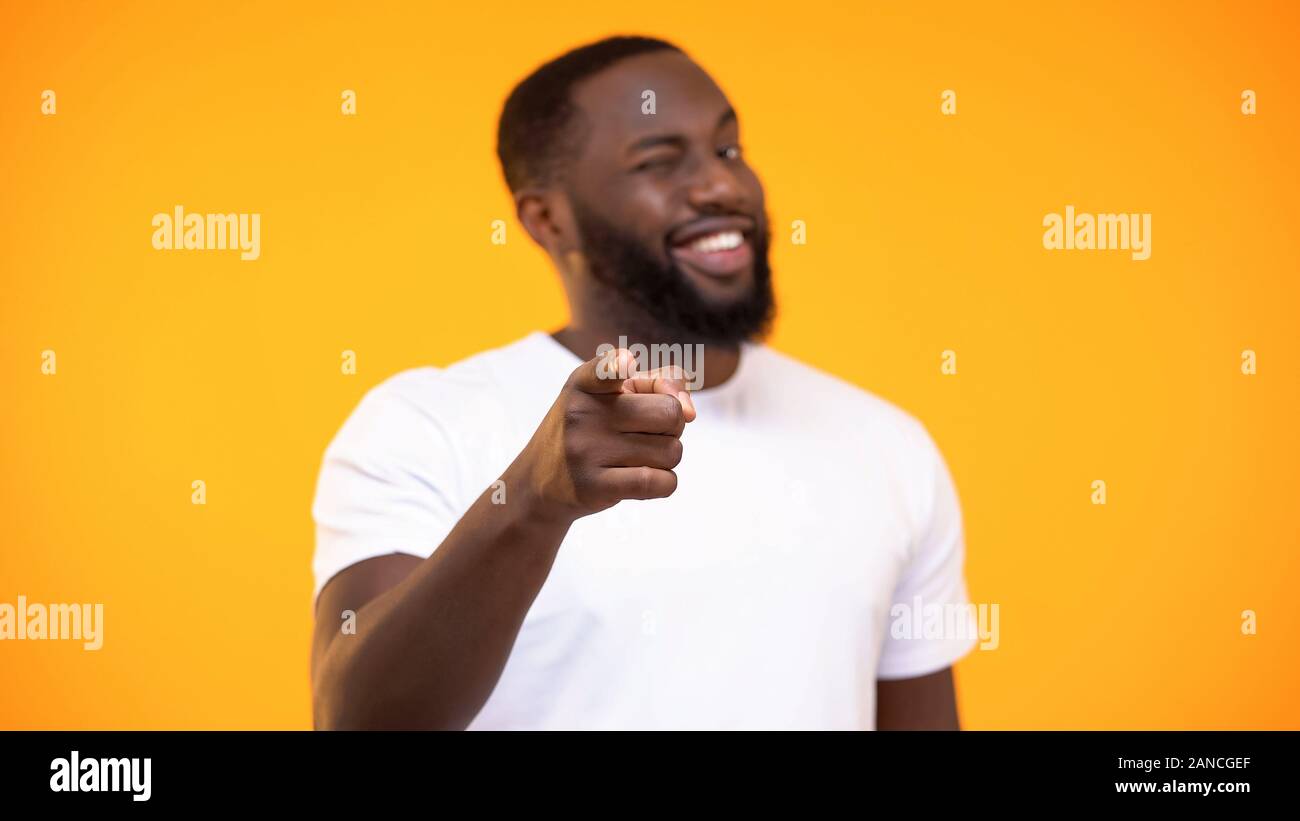 Young black man pointing finger on camera and smiling against yellow background Stock Photo