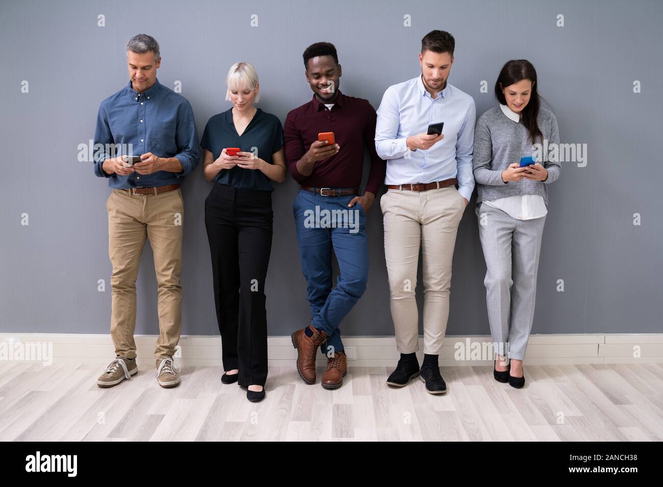 Row Of Diverse Businesspeople Using Phones In Office Stock Photo