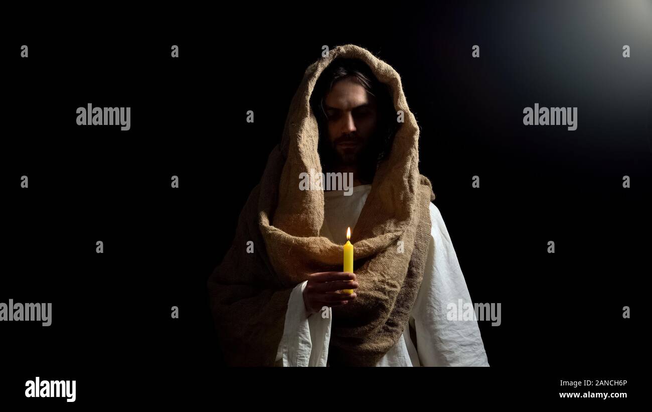 Messiah holding candle, praying for people sins expiation, belief and kindness Stock Photo